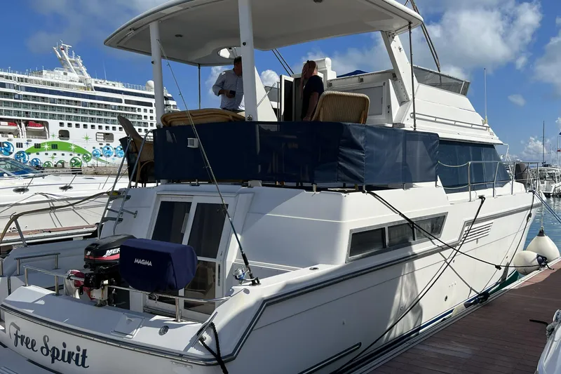 Slide: The Image of 1999 Carver 430 Cockpit Motor Yacht docked at marina, with cruise ship in background. - 39