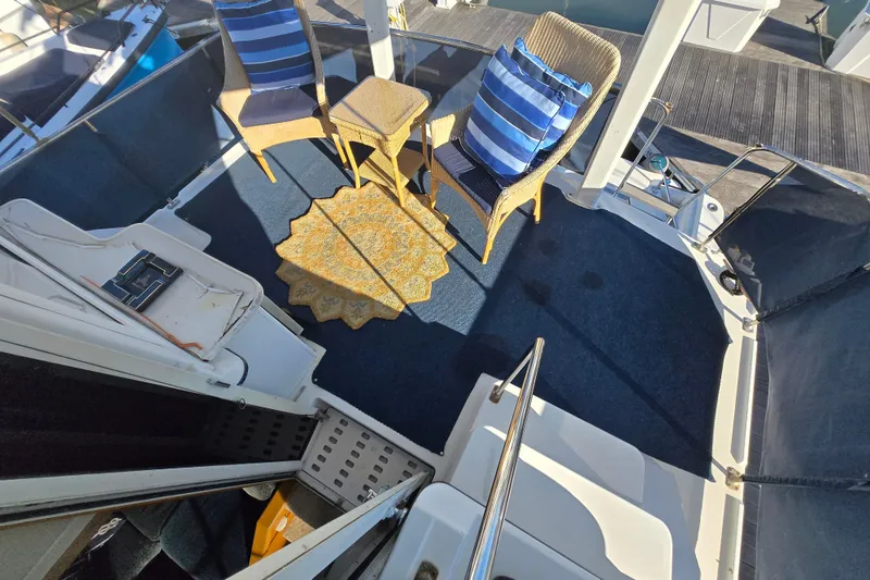Slide: The Image of 1995 Carver 430 Cockpit Motor Yacht deck with chairs, striped cushions, and a decorative rug. - 6