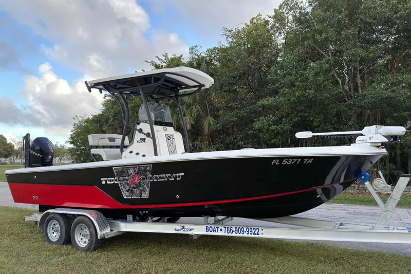 The Image of 2019 Wellcraft 241 Bay boat on trailer, black and red design, parked outdoors. - 1