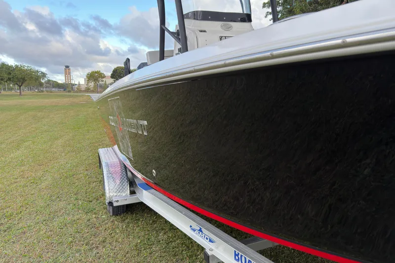 Slide: The Image of 2019 Wellcraft 241 Bay boat on trailer, parked on grass under cloudy sky. - 10