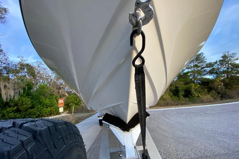 Slide: The Image of 2020 Pathfinder 2500 Hybrid boat on trailer, secured with strap, parked near trees. - 12