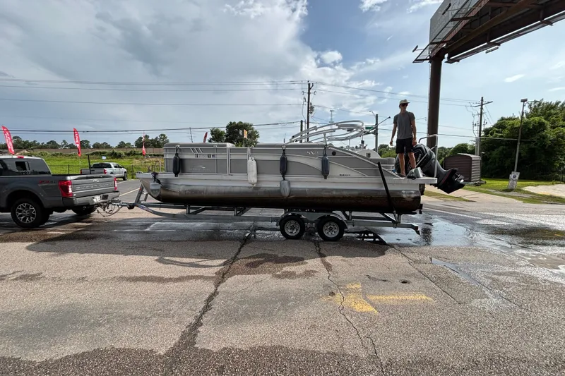 The Image of 2023 Bennington 23 SXSB pontoon boat on trailer, parked outdoors under cloudy sky. - 1