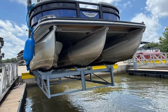Slide: The Image of 2023 Bennington 23 SXSB pontoon boat on lift, dockside, under clear blue sky. - 6