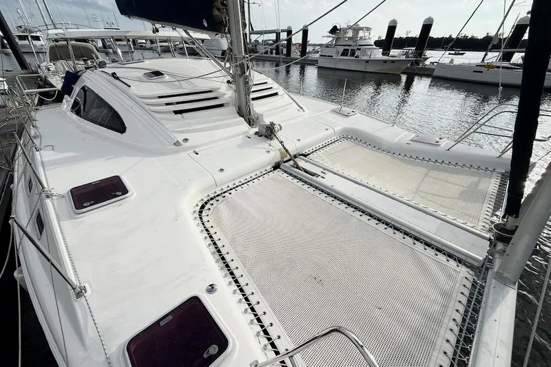 Slide: The Image of 2006 Island Spirit 401 catamaran docked, featuring spacious deck and netting. - 11