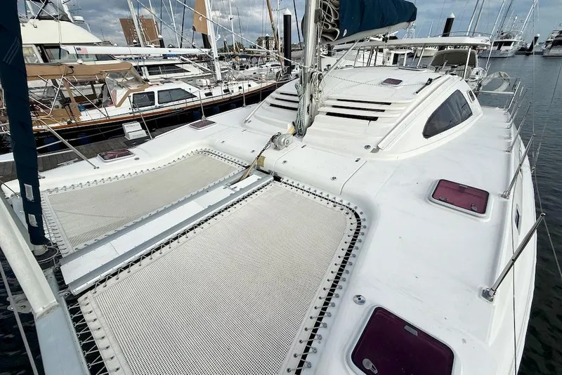 Slide: The Image of 2006 Island Spirit 401 catamaran docked at marina, showcasing spacious deck and netting. - 12