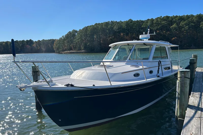 Slide: The Image of 2008 Back Cove 33 boat docked on a serene lake with forested background. - 2