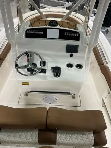 Slide: The Image of 2025 Pioneer Islander 222 boat console with steering wheel and controls, featuring brown seating. - 3