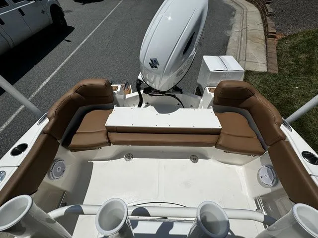 Slide: The Image of 2025 Pioneer ISLANDER 202 boat with brown seating and outboard motor, parked on a street. - 11