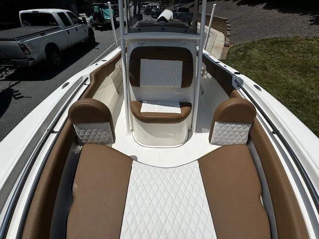 Slide: The Image of 2025 Pioneer ISLANDER 202 boat interior with brown and white seating, parked on a street. - 9