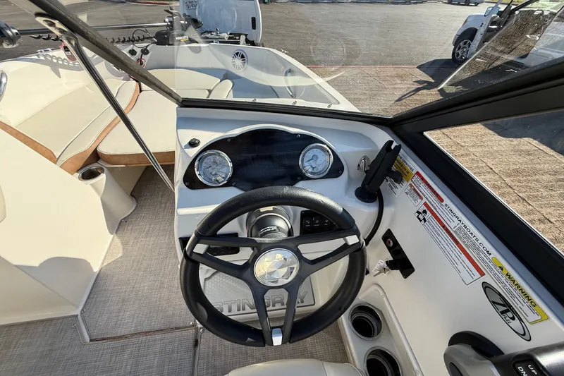 Slide: The Image of 2023 Stingray 192 DC boat interior with seating, docked by a calm lake. - 32