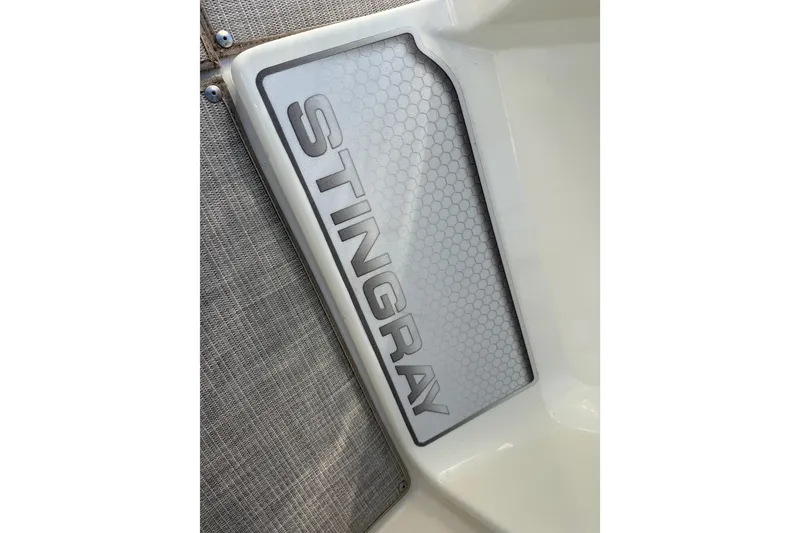 Slide: The Image of 2023 Stingray 192 DC boat interior with beige and brown seating, near water. - 34