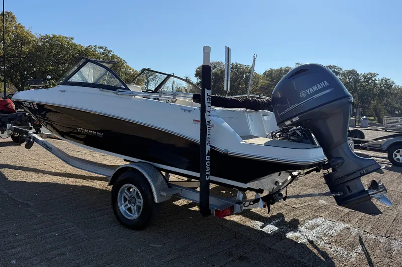 Slide: The Image of 2023 Stingray 192 DC boat on trailer by a lake, clear sky background. - 4