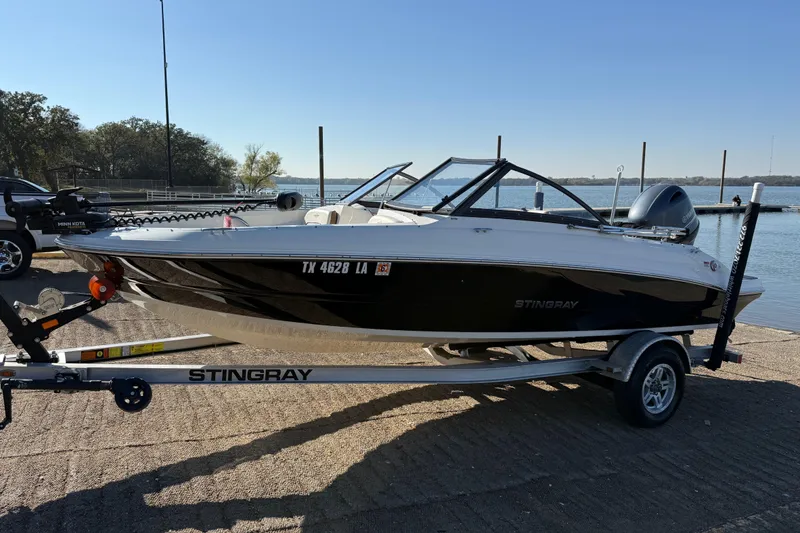 Slide: The Image of 2023 Stingray 192 DC boat on trailer with Yamaha outboard motor, parked near a lake. - 6