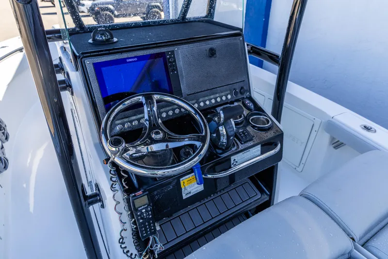 Slide: The Image of 2018 Crevalle 26 Open boat dashboard with steering wheel and navigation controls. - 2