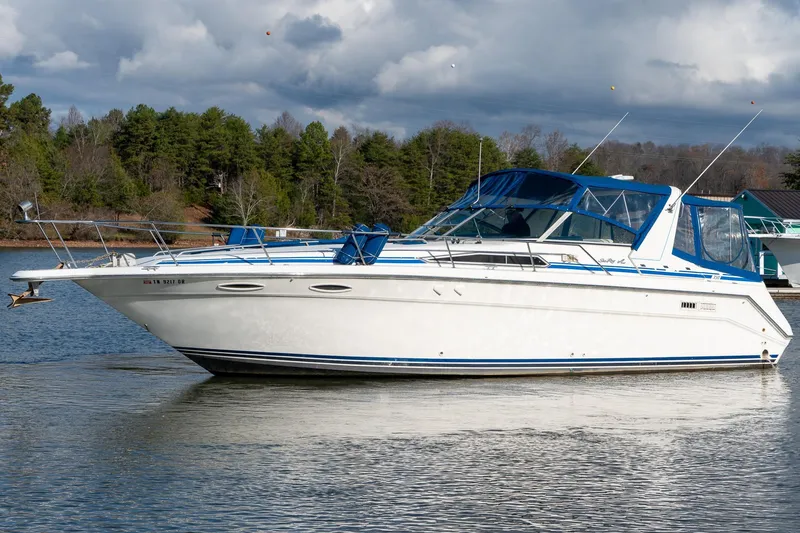 The Image of 1991 Sea Ray 350 Sundancer boat on a calm lake with forested shoreline. - 1