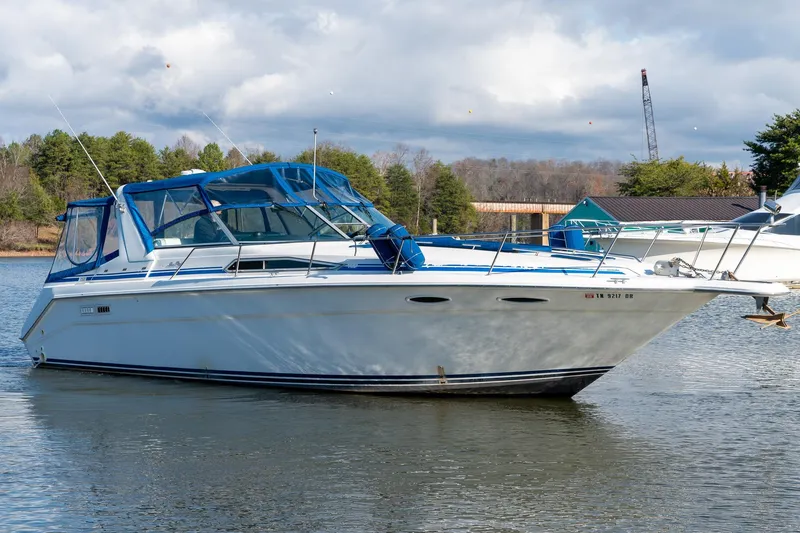 Slide: The Image of 1991 Sea Ray 350 Sundancer boat on calm water with blue canopy. - 4
