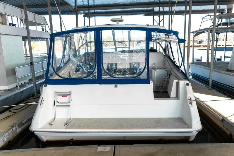 Slide: The Image of 1991 Sea Ray 350 Sundancer docked, featuring blue canopy and spacious rear deck. - 8