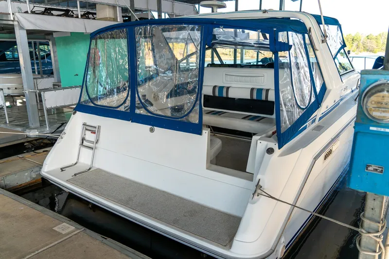 Slide: The Image of 1991 Sea Ray 350 Sundancer docked, featuring blue canopy and spacious seating area. - 9