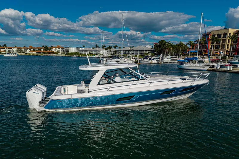 Slide: The Image of 2024 Intrepid 477 Evolution boat cruising in a marina under a clear blue sky. - 1
