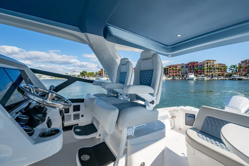 Slide: The Image of 2024 Intrepid 477 Evolution yacht helm with luxurious seating and waterfront view. - 30