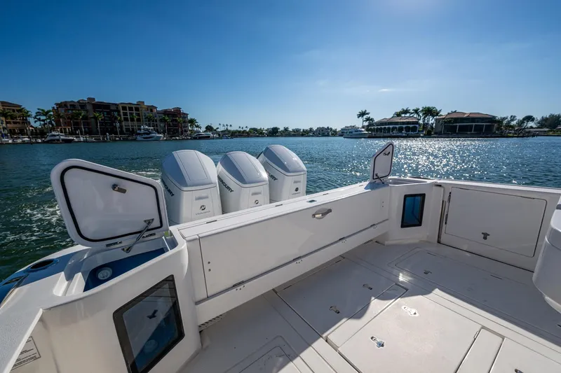 Slide: The Image of 2024 Intrepid 477 Evolution boat with open hatches, docked by waterfront homes. - 36