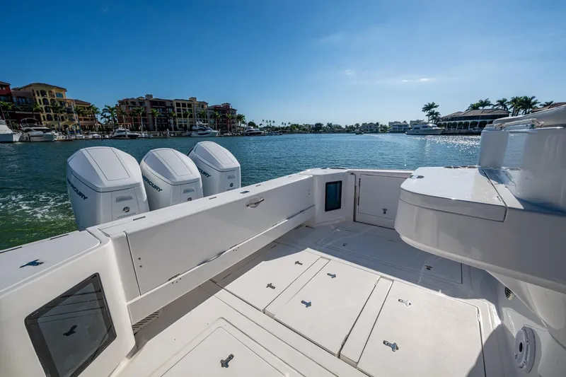 Slide: The Image of 2024 Intrepid 477 Evolution boat with triple Mercury engines, docked in a scenic marina. - 37