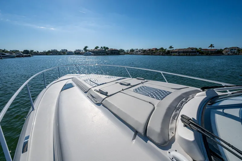 Slide: The Image of 2024 Intrepid 477 Evolution yacht cruising on a sunny day, with waterfront homes in the background. - 45