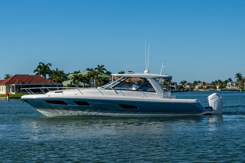 Slide: The Image of 2024 Intrepid 477 Evolution yacht cruising on a sunny day near waterfront homes. - 5