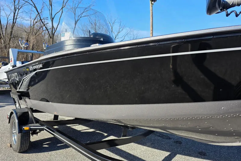 Slide: The Image of 2022 Lund 1675 Adventure SS boat on trailer, black exterior, parked outdoors. - 3