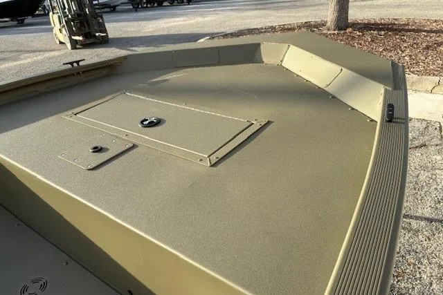 Slide: The Image of 2026 Tracker Grizzly 1648 Utility boat, olive green deck, parked outdoors. - 4