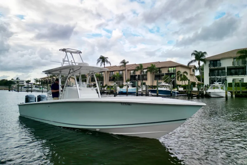 Slide: The Image of 2005 Jupiter 31 Center Console boat docked near waterfront homes under cloudy sky. - 2