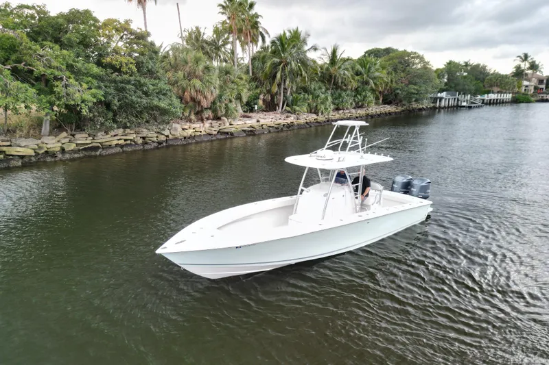 Slide: The Image of 2005 Jupiter 31 Center Console boat cruising on a scenic waterway with lush greenery. - 7