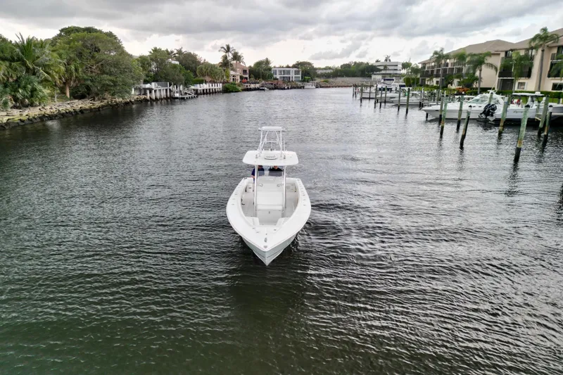 Slide: The Image of 2005 Jupiter 31 Center Console boat on a calm waterway, surrounded by lush greenery and docks. - 8