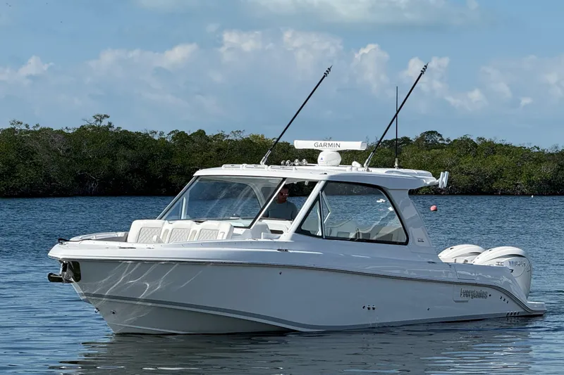 Slide: The Image of 2026 Everglades 367 CX boat on calm water with lush greenery background. - 2