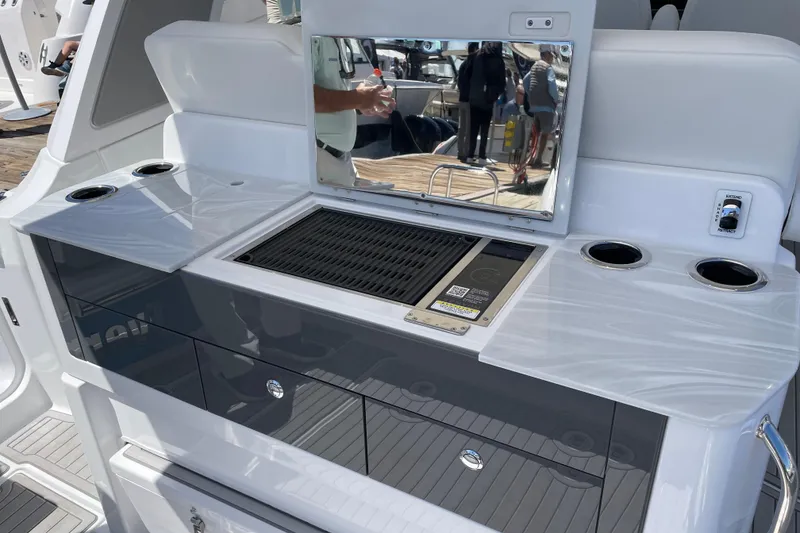 Slide: The Image of Luxury outdoor kitchen on 2026 Everglades 367 CX boat, featuring grill and cup holders. - 8