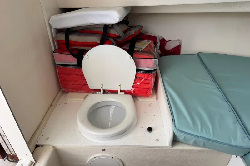 Slide: The Image of 1997 Parker 2510 Walkaround boat interior with toilet, life jackets, and cushions. - 13