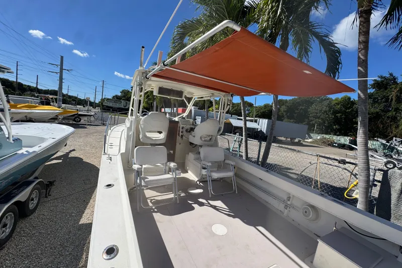 Slide: The Image of 1997 Parker 2510 Walkaround boat with orange canopy, parked outdoors under palm trees. - 3