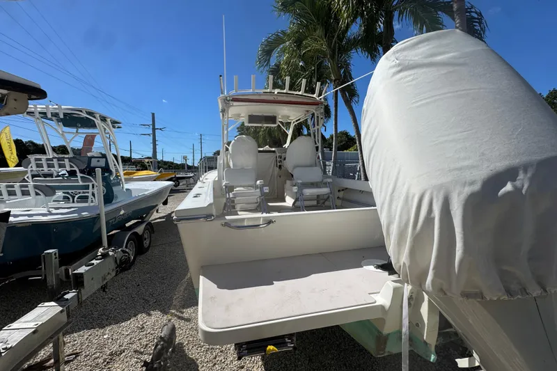 Slide: The Image of 1997 Parker 2510 Walkaround boat with covered engine, parked outdoors under clear sky. - 6