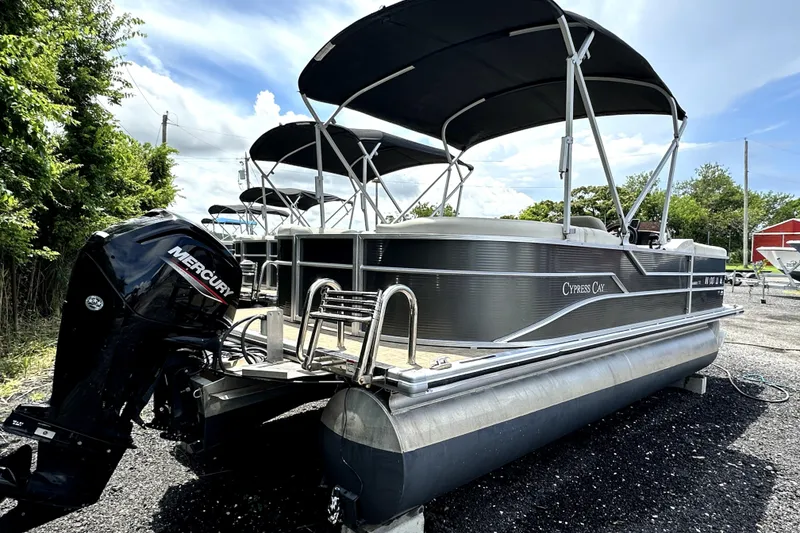 Slide: The Image of 2022 Cypress Cay Seabreeze 232 pontoon boat with Mercury outboard motor, parked outdoors. - 2