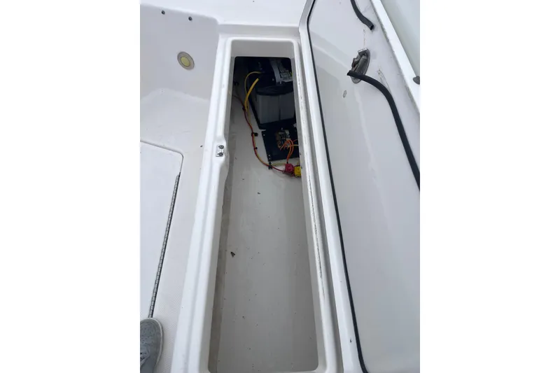 Slide: The Image of Open storage compartment on 2012 Everglades 295 Center Console boat, showing wiring and battery. - 31