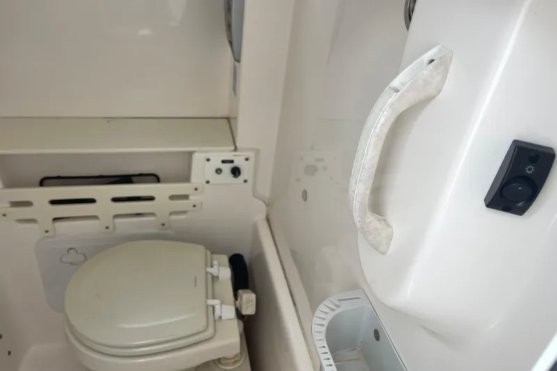 Slide: The Image of Interior of 2012 Everglades 295 Center Console boat, featuring a compact marine toilet. - 33