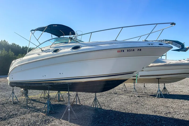Slide: The Image of 2000 Sea Ray 260 Sundancer boat on stands in a gravel lot. - 1