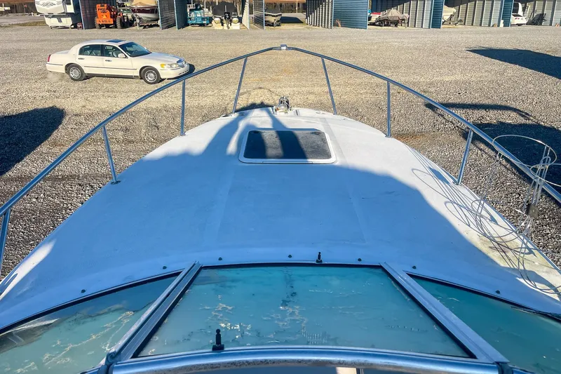 Slide: The Image of 2000 Sea Ray 260 Sundancer boat on gravel lot, with parked car in background. - 18