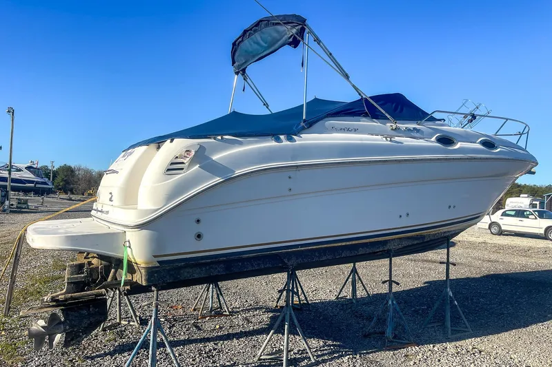Slide: The Image of 2000 Sea Ray 260 Sundancer boat on stands in a gravel lot, blue canopy. - 3