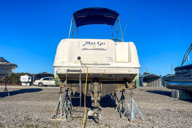 Slide: The Image of 2000 Sea Ray 260 Sundancer boat on stands, outdoor storage, clear blue sky. - 6
