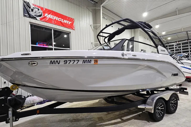 The Image of 2024 Yamaha Boats 222SE in showroom, sleek white design on trailer. - 1