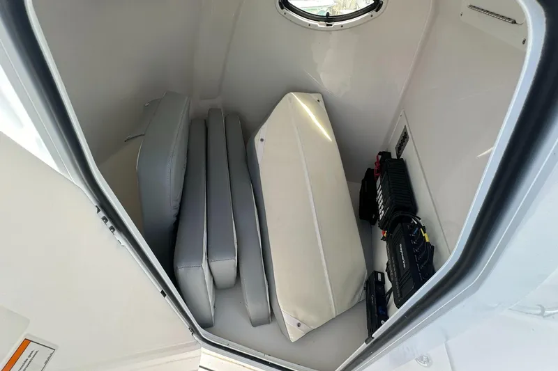 Slide: The Image of 2025 Twin Vee 260 GFX2 CC storage compartment with cushions and electronic equipment. - 7