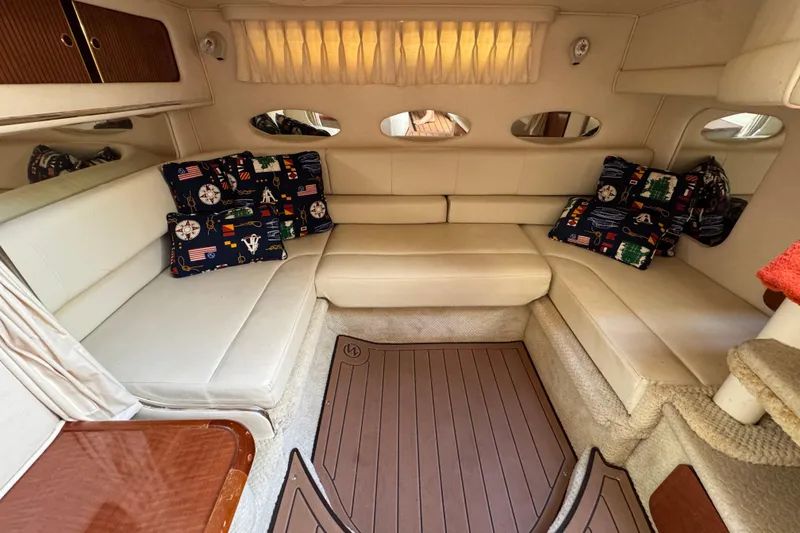 Slide: The Image of Interior of 2002 Sea Ray 310 Sundancer with cozy seating and nautical-themed cushions. - 10