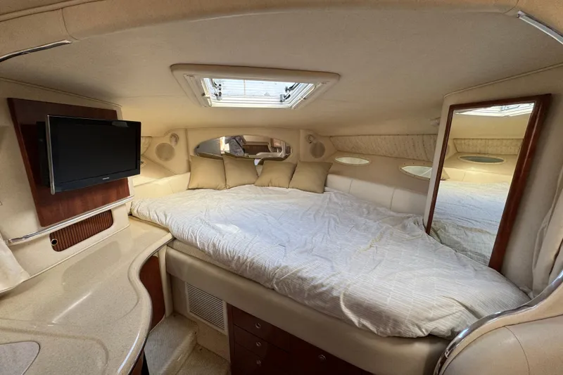 Slide: The Image of Luxurious interior cabin of a 2002 Sea Ray 310 Sundancer with cozy bedding and a TV. - 13