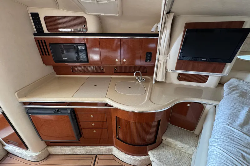 Slide: The Image of 2002 Sea Ray 310 Sundancer interior with kitchenette, microwave, and TV. - 14